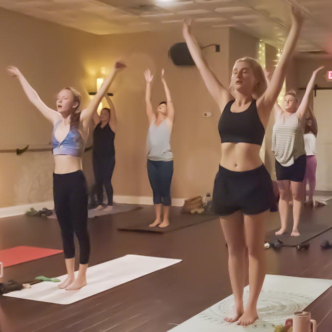 Group yoga class practicing standing poses together in a calm studio